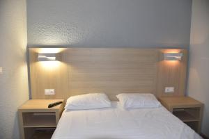 a bed with two white pillows and two night stands at FastHotel Thionville in Thionville