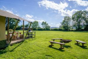 a tent with benches and a grill in a field at The Firs Glamping in Welland