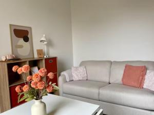 a living room with a couch and a table with flowers at Studio Cosy avec Terrasse - Gare a 2min & wifi in Compiègne