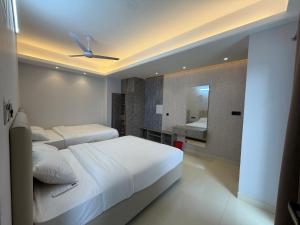 a bedroom with two beds and a bathroom with a mirror at Hotel Moon Light in Dhaka