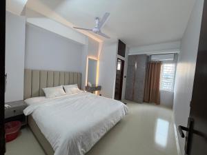 a bedroom with a white bed with a ceiling fan at Hotel Moon Light in Dhaka