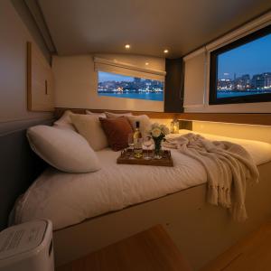 a large bed in a room with two windows at Barco Different Charter - Experiencia Única en el Puerto Deportivo de Vigo in Vigo
