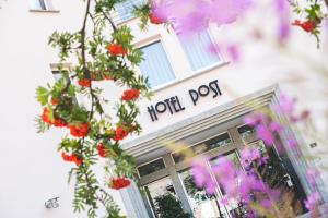 a front door of a hot dog shop with flowers at Hotel Post Sils Maria in Sils Maria
