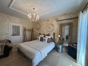 a bedroom with a large white bed and a chandelier at Le Relais de la Chouette in Berson