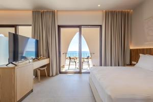 a hotel room with a bed and a desk with a television at Ulin Boutique Hotel in Borsh