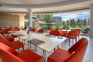 a dining room with tables and chairs and a building at Ramla Bay Resort in Mellieħa