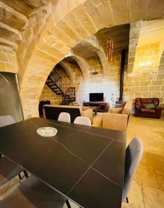 a table and chairs in a room with a stone wall at Mithna farmhouse in Għarb
