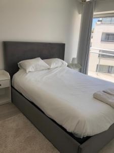 a bed with white sheets and a large window at T1 Figueira da Foz in Buarcos