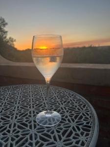a glass of wine sitting on a table with the sunset at Matopos Loft in Stilbaai-Wes