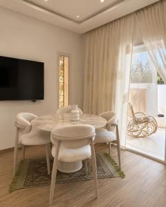 a dining room with a table and chairs and a television at Kefia house in Hammamet Nord