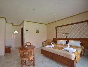 a bedroom with two swans on a bed and a table at Angelina Hotel & Apartments in Sidari +29 photos
