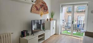 a living room with a television and a balcony at casa Chloe in Ourense