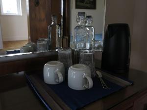 a counter with two mugs and glasses on a table at Farmhouse with Loch Views in Gartocharn