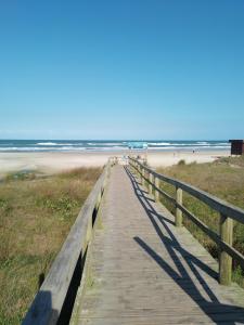 a boardwalk to the beach with the ocean in the background at Apartamento junto mar, bem ventilado e iluminado - Antilhas 679 in Capão da Canoa