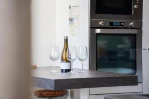 a bottle of wine and three wine glasses on a counter at 41 Maufoux By Bruno Colin - Parenthèse Élégante à Beaune in Beaune +28 photos