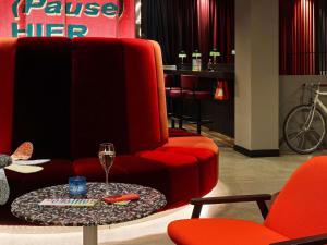 a living room with a red chair and a table at 25hours Hotel beim MuseumsQuartier in Vienna