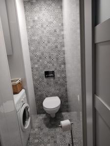 a bathroom with a toilet and a tiled floor at Apartament Przyjaźń in Tarnowskie Góry