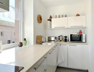 a white kitchen with white cabinets and a microwave at Gîte Théophile Fenal in Badonviller +11 photos