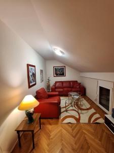 a living room with a red couch and a table at MÐM Duplex Apartment in Podgorica