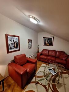 a living room with red leather couches and a glass table at MÐM Duplex Apartment in Podgorica