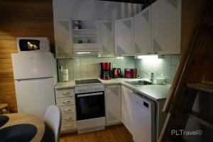 a small kitchen with white cabinets and a white refrigerator at Holidayhome Sompio in Luosto +20 photos