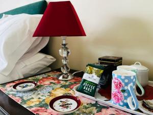 a bedside table with a lamp and a table with a nightstand at Garwood House in Holt