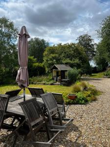 an umbrella sitting on a wooden table with chairs at Garwood House in Holt