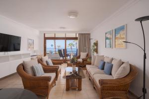 a living room with a couch and chairs and a television at Sunsuites Carolina in San Agustin +10 photos