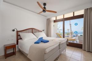 a bedroom with a bed with a ceiling fan and a balcony at Sunsuites Carolina in San Agustin