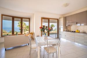 a kitchen and dining room with a table with flowers on it at Villa Chiara Infinity Sea View in Mandaradoni +60 photos
