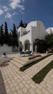 a building with two blue benches in front of it at Kefia house in Hammamet Nord