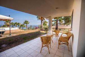 a patio with chairs and a table with a view of the ocean at Villa Chiara Infinity Sea View in Mandaradoni