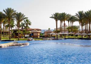 a pool at a resort with palm trees and umbrellas at Tropitel Sahl Hasheesh in Hurghada