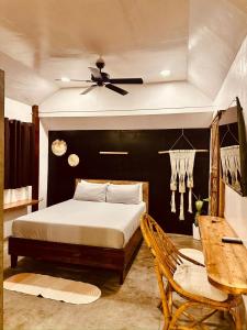 a bedroom with a bed and a table and a ceiling fan at Happiness Beach Resort Siargao in General Luna