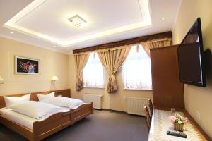 a bedroom with a bed and a flat screen tv at Hotel Europäischer Hof in Elsterwerda