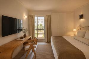 a bedroom with a bed and a desk with a television at Masana Algarve, Destination by Hyatt in Albufeira