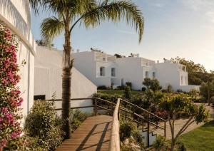 a staircase leading to a white house with a palm tree at Masana Algarve, Destination by Hyatt in Albufeira