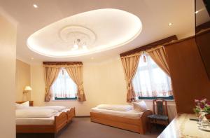 a bedroom with two beds and a white ceiling at Hotel Europäischer Hof in Elsterwerda