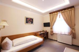 a bedroom with a bed and a desk and a window at Hotel Europäischer Hof in Elsterwerda
