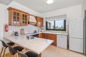 a kitchen with a counter and a white refrigerator at Melia Villa II by Nomads in Kissonerga