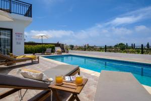 a swimming pool with a table with orange juice at Melia Villa II by Nomads in Kissonerga