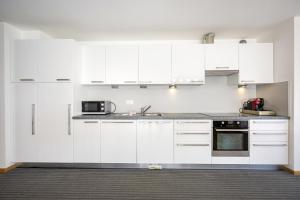 a white kitchen with white cabinets and appliances at Apartments Villa Jim in Ortisei