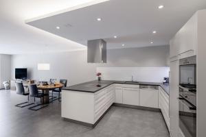 a kitchen with white cabinets and a table and a dining room at Chasa Miramunt 2 in Scuol