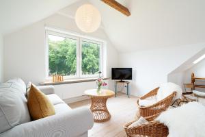 a living room with a white couch and wicker chairs at Ferienhaus Stranden Westfehmarn in Fehmarn