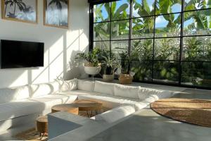 a living room with a white couch and a large window at The Young Villas - Canggu in Canggu