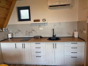 a kitchen with white cabinets and a sink and a window at Maple Valley in Žabljak +25 photos