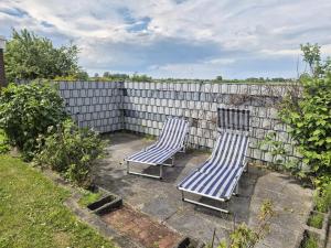 two lounge chairs sitting on a patio next to a fence at Feldblick in Krummhörn