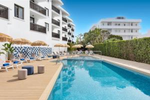 a swimming pool with chairs and umbrellas next to a building at HSM Lago Park in Playa de Muro