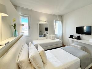 a hotel room with two beds and a tv at B&B Carmen Garden in Burano