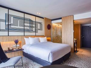 a bedroom with a large white bed and a chair at Pullman Lima Miraflores in Lima